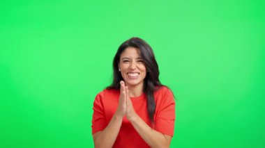 Coşkulu genç bir kadın el çırpıyor ve krom bir arka plana karşı kutlama yapıyor.