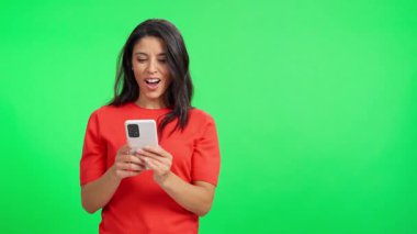 Genç kadın cep telefonuna bakıyor ve zaferi heyecanla kutluyor.