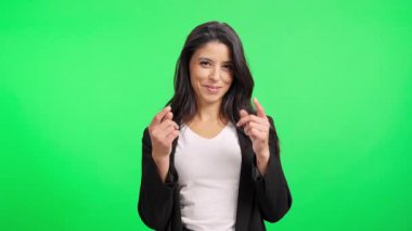 Uzun siyah saçlı, gülümseyen bir kadın. Krom anahtar arka planına karşı para hareketi yapıyor.