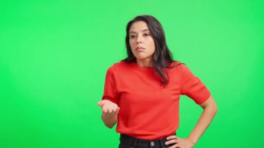 Kafası karışmış beyaz kadın kameraya bakıyor. Kafası karışık ve yeşil arka planda sorgulanıyor.