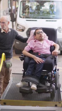 Elektrikli sandalyedeki genç adam ulaşılabilir bir minibüs kullanıyor.