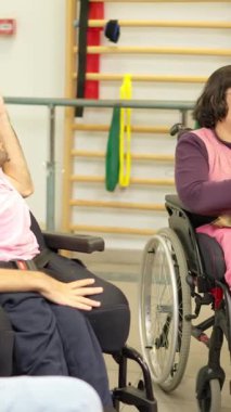 Fiziksel engelli bir grup yetişkin rehabilitasyon merkezinde top atarken eğleniyor.