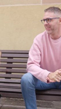 İki erkek arkadaş parkta bir bankta otururken sohbet ediyorlar.