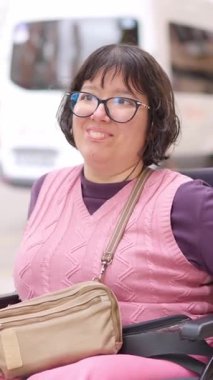 Fiziksel engelli bir kadının portresi tekerlekli sandalyede oturuyor ve dışarıda gülümsüyor.