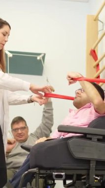 Fiziksel engelli genç bir adam rehabilitasyon egzersizleri yapıyor. Kadın bir terapistin yardımıyla.