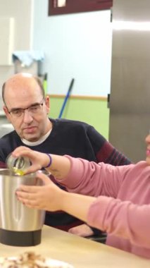 Fiziksel engelli insanlar uyum sağlamış bir mutfakta aşçılık kursu sırasında birlikte yemek hazırlıyorlar.