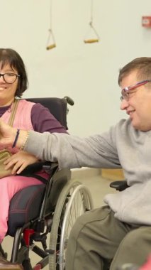 Tekerlekli sandalyedeki mutlu insanlar rehabilitasyon merkezinde eğlenceli bir grup aktivitesi yapıyorlar.