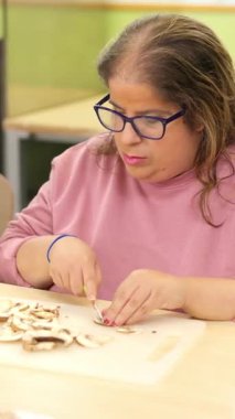 Fiziksel engelli özel bir kadın yemek hazırlamak için mantar doğramaya odaklanmış.