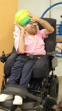 Fizik tedavi seansı sırasında topla oynayan fiziksel engelli bir genç.