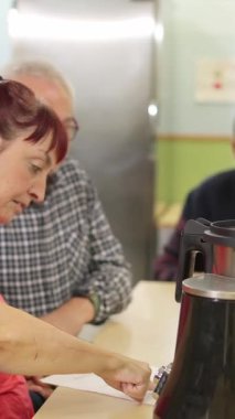 Kolunda fiziksel engeli olan orta yaşlı bir kadın bir adamın yanında belge imzalıyor.