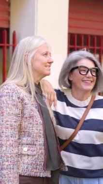 Mutlu kıdemli arkadaşlar, şehirde boş vakitlerini geçirirken gülümseyip sohbet ediyorlar.