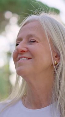 Güzel yaşlı kadın dışarıda huzurlu bir anın tadını çıkarıyor, mutluluk ve mutlulukla gülümsüyor.