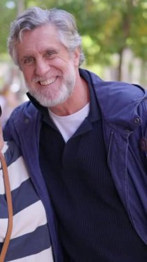 Büyüleyici, olgun bir çift güzel bir günün tadını çıkarıyor. Kameraya sarılıp gülümsüyorlar.