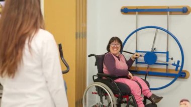 Fizyoterapistiyle klinikte rehabilitasyon egzersizleri yapan mutlu bir kadın.