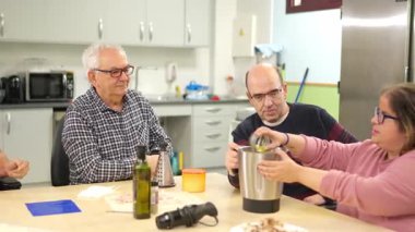 Fiziksel engelli insanlar uyum sağlamış bir mutfakta aşçılık kursu sırasında birlikte yemek hazırlıyorlar.