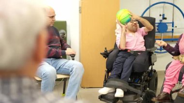 Fizik tedavi seansı sırasında topla oynayan fiziksel engelli bir genç.