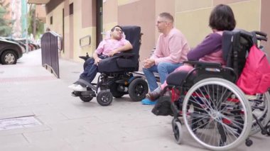 İki adam ve fiziksel engelli bir kadın bir caddede dostça sohbet ediyorlar.