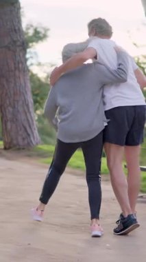 Olgun, beyaz bir çift, güneşli bir günde parkta neşeyle dans ediyor.