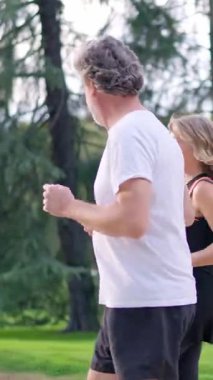 Açık havada birlikte koşarken sağlıklı bir yaşam tarzının tadını çıkaran gri saçlı aktif son sınıf çifti.