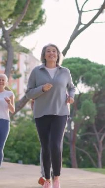 Aktif son sınıf öğrencisi, güzel gri saçlı bir grup arkadaşa parkta koşarken liderlik ediyor.