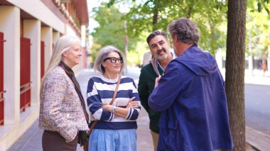 Olgun arkadaşlar, şehrin caddesinde ağır çekimde dururken keyifli bir sohbetin tadını çıkarıyorlar.