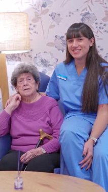 Huzurevinde oturan yaşlı bir hastayla ilgilenen arkadaş canlısı bayan hemşire.