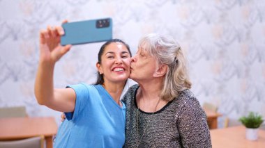 Torun, mutlu büyükanneyi yanağından öperken selfie çekiyor.