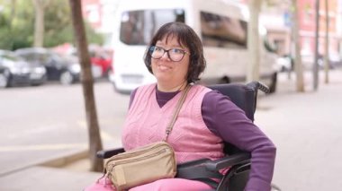 Fiziksel engelli bir kadının portresi tekerlekli sandalyede oturuyor ve dışarıda gülümsüyor.