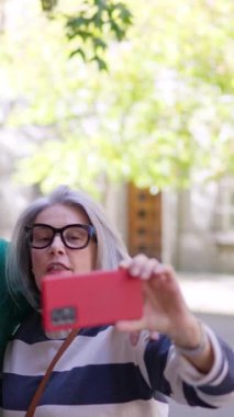 Mutlu bir grup olgun arkadaş parkta selfie çekmek için cep telefonu kullanıyor.