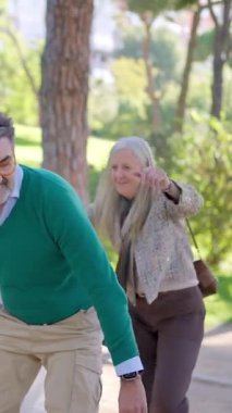 Neşeli son sınıf çifti, kadını sırtında taşıyan adamla parkta eğleniyor.