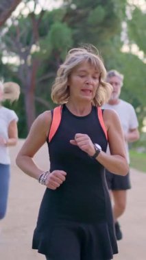 Bir grup olgun arkadaş dışarıda birlikte egzersiz yaparken sağlıklı bir yaşam tarzının tadını çıkarıyorlar.