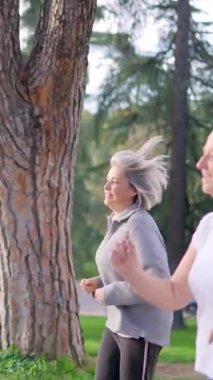 Bir grup aktif son sınıf öğrencisi parkta birlikte koşuyor ve ağır çekimde sağlıklı kalıyorlar.