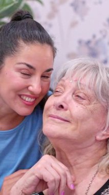 Şefkatli torun, mutlu büyükannesini yanağından öpüyor ve aile bağlarını gösteriyor.