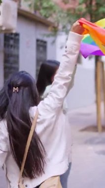 Igbt Onur Yürüyüşü 'nde gökkuşağı bayrağını sallayan iki genç kadının arka görüntüsü