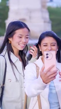 İki neşeli, etnik çeşitlilikte kadının cep telefonuyla fotoğraf çekmesinin ağır çekimleri.