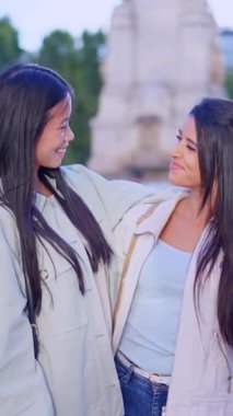 Mutlu, çok ırklı lezbiyen çift parkta birbirlerine sarılıp gülüyorlar.