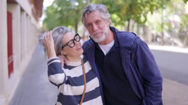 Büyüleyici, olgun bir çift güzel bir günün tadını çıkarıyor. Kameraya sarılıp gülümsüyorlar.