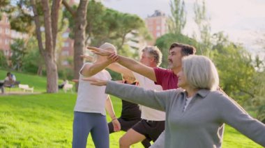 Yeşil bir parkta açık hava dersi sırasında yoga yapan bir grup gülümseyen son sınıf öğrencisi.
