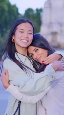 Aynı cinsiyet ilişkisindeki iki mutlu çok ırklı kadın bir parkta şefkatle kucaklaşıyor.