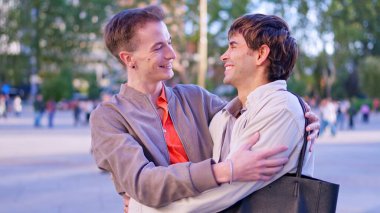 Dışarıda kucaklaşan eşcinsel çift, kapsama ve mutluluğu kutluyor.