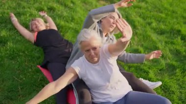 Güneşli bir parkta egzersiz yapan ve birlikte gülen iki olgun kadın.
