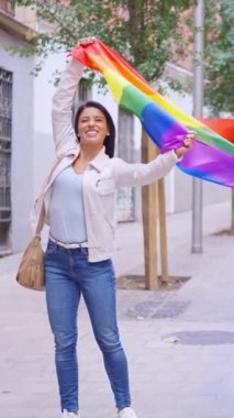 Sokakta yürürken LGBT gökkuşağı bayrağını sallayan ve öpen mutlu kadın