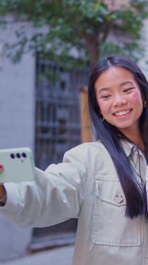 Mutlu çok ırklı arkadaş grubu akıllı telefonuyla selfie çekiyor ve şehirde eğleniyor.