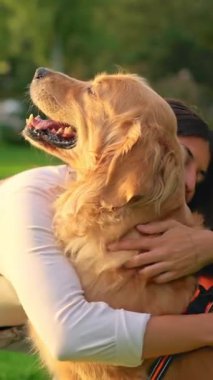 Mutlu genç bir kadın güneşli bir günde güzel köpeğini kucaklıyor.