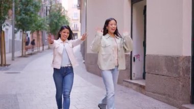 Ağır çekimde arkadaşlarına sarılmak için kollarını açıp koşan genç kadınlar.