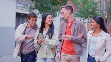 Genç bir kadın sokakta birlikte cep telefonu kullanırken arkadaşlarıyla gülüyor.