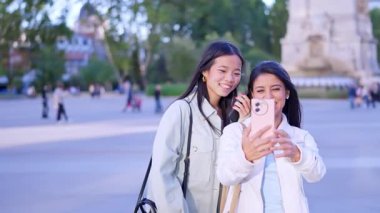 İki neşeli, etnik çeşitlilikte kadının cep telefonuyla fotoğraf çekmesinin ağır çekimleri.