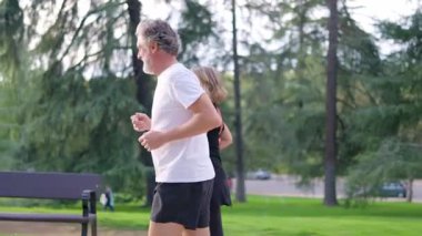 Açık havada birlikte koşarken sağlıklı bir yaşam tarzının tadını çıkaran gri saçlı aktif son sınıf çifti.