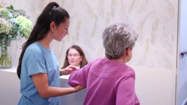 Genç kız torun büyükannesine destek oluyor.