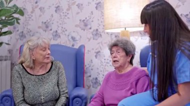 İki kıdemli kadın asistan emekliler cemiyetinde genç bakıcılarıyla konuşuyor.